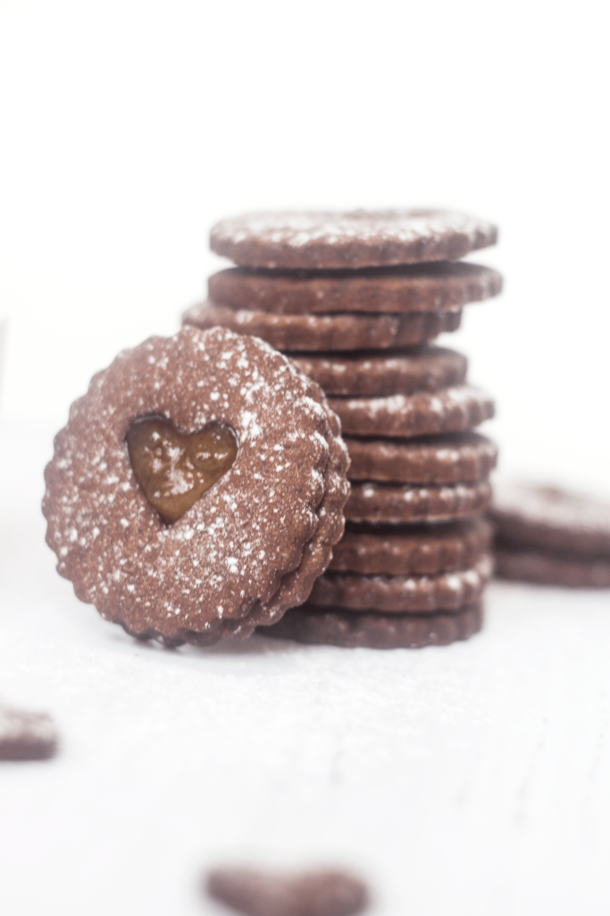 stacked Chocolate Orange Linzer Cookies on a white background