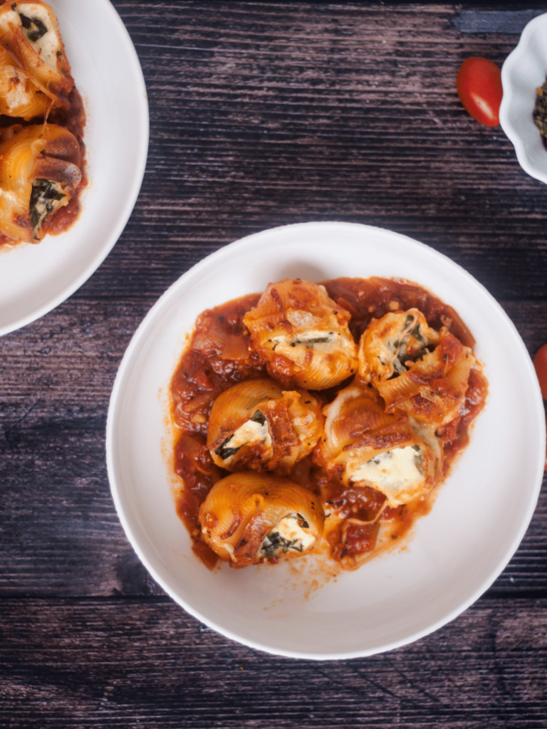 ricotta and spinach stuffed shells in white plate on dark background