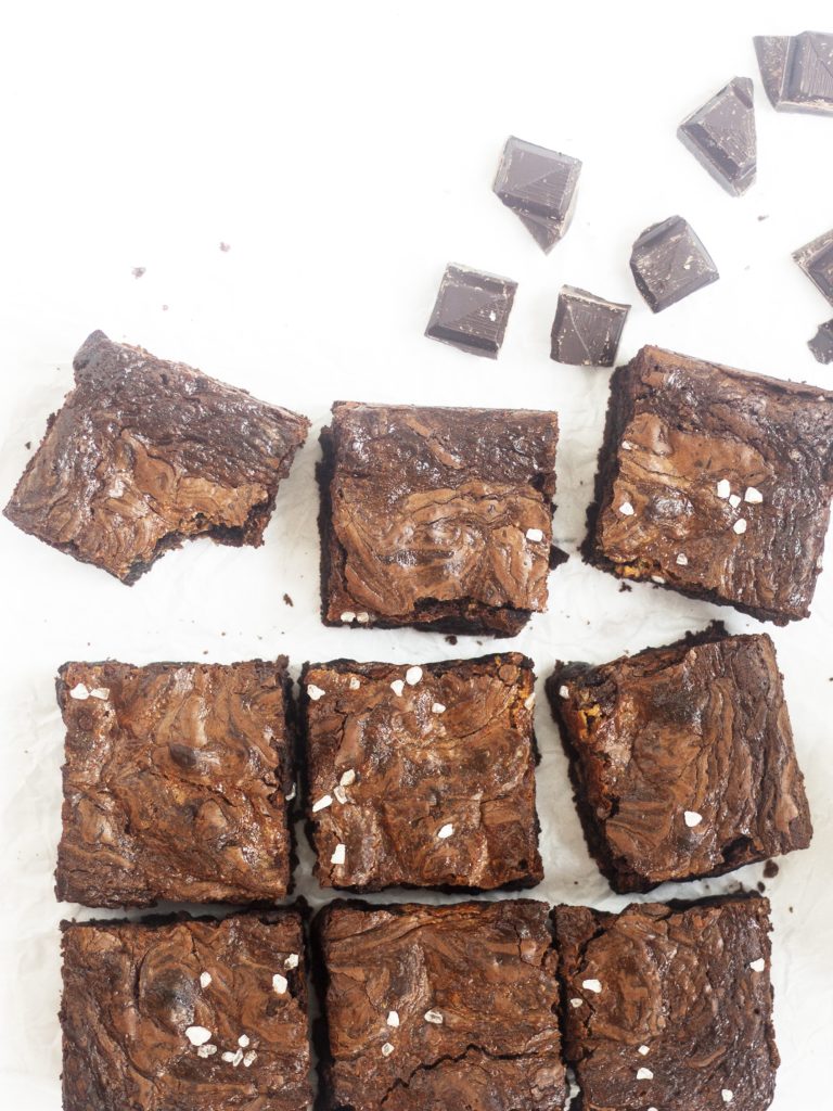 Dulce de Leche Chocolate Brownies on a white backgroun surrounded by chocolate pieces