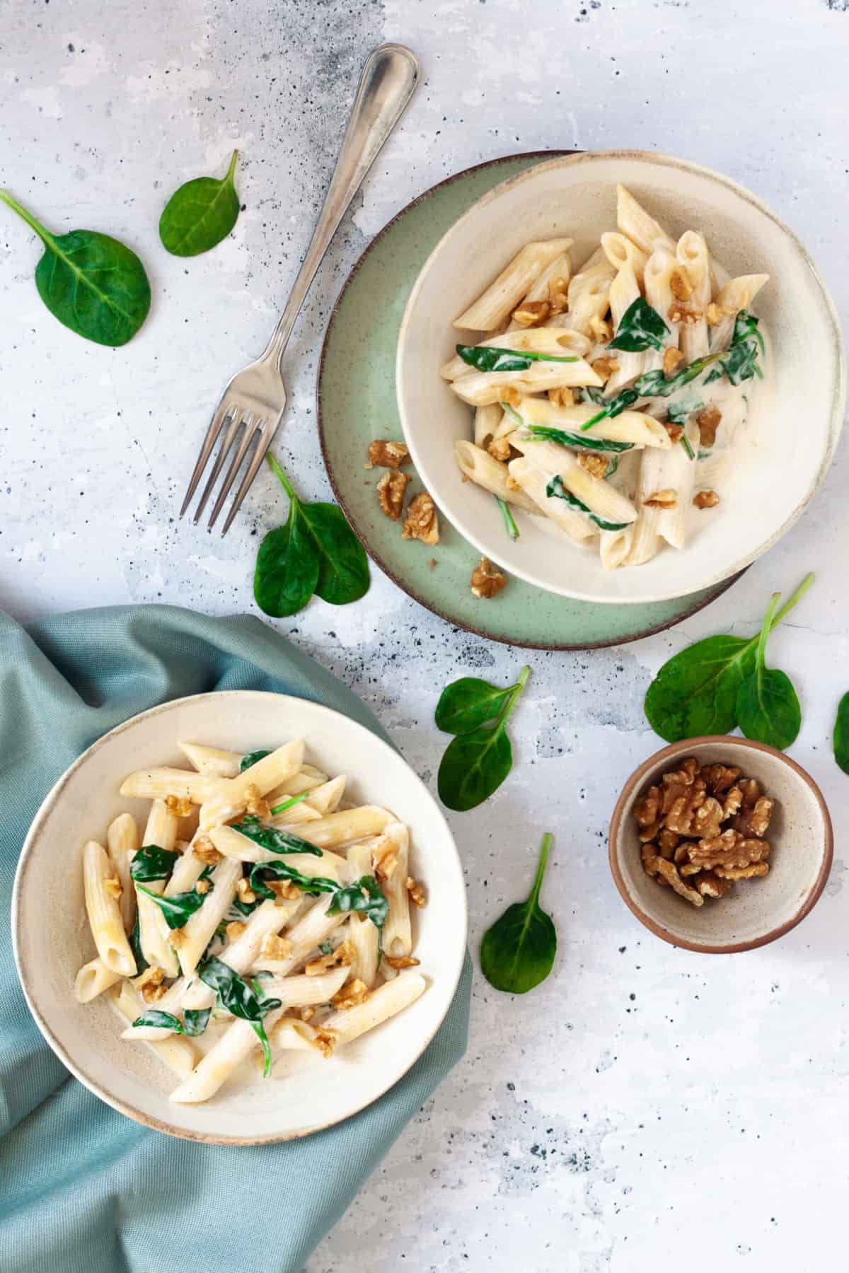 vertical image of creamy spinach and walnut pasta plates