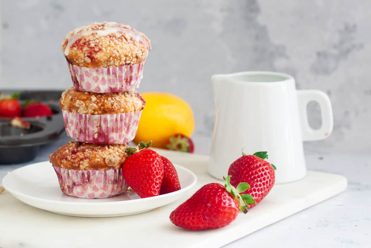 stacked Eggless Strawberry Swirl Muffins surrounded by fresh strawberries