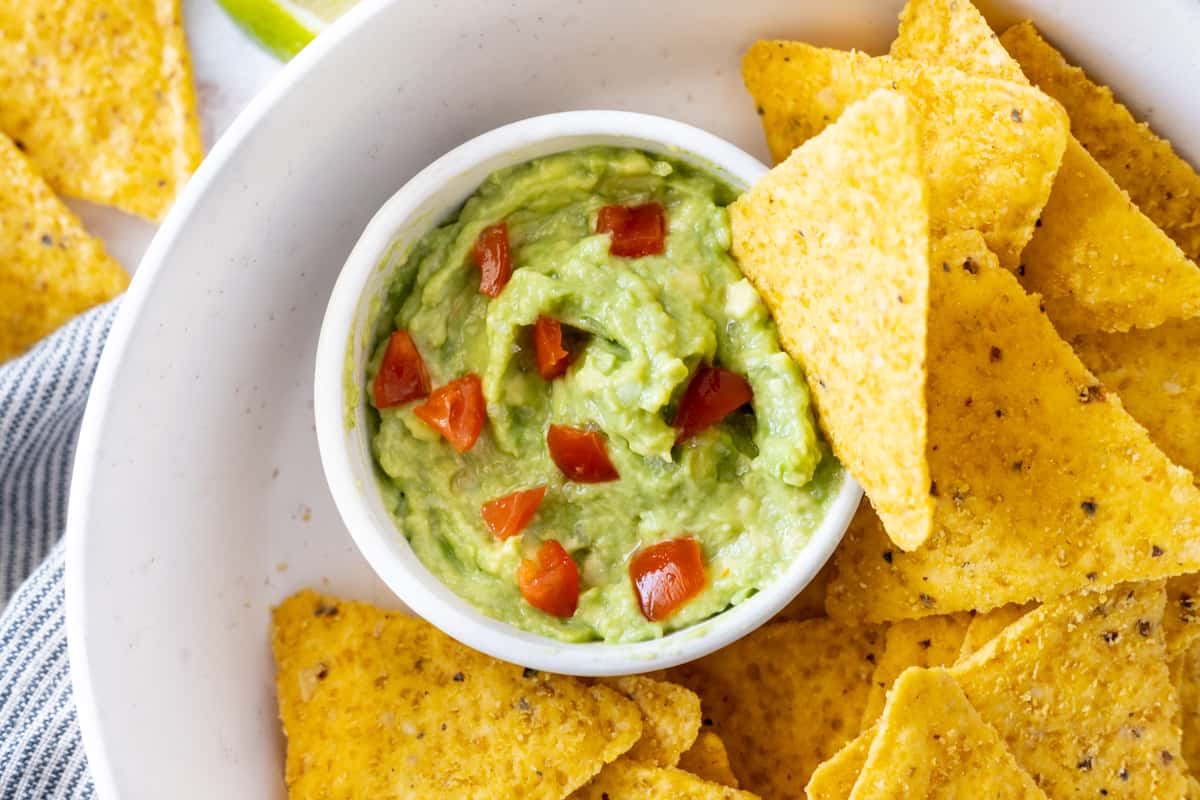 4 Ingredients Guacamole in a small bowl surrounded by tortilla chips.